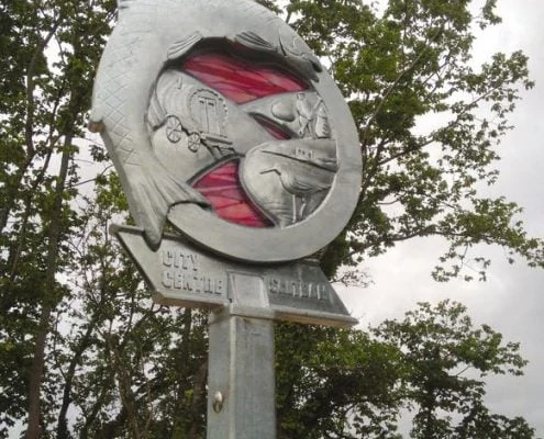 Waymarker Plym Valley Heritage Trail pink sunset glass. Saltram Ride | Plymouth | Thrussells Waymarker sign made of metal and pink glass. Fish and railway themed. Plymouth public art