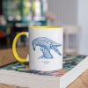 Two tone white and yellow mug with Thrussells blue bird on book