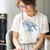 Woman reading with white t-shirt with Thrussells blue bird