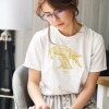 Woman reading with white t-shirt with Thrussells yellow bird